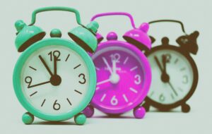 Vibrant set of vintage alarm clocks in teal, pink, and black.